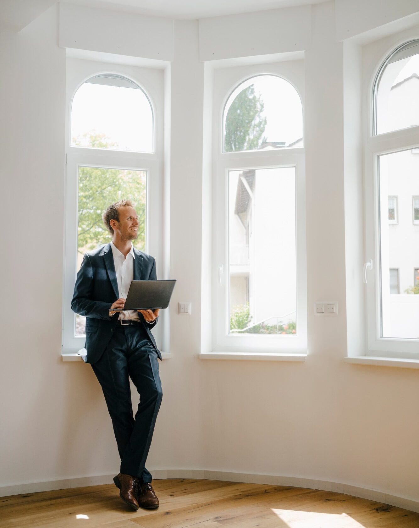 Estate agent waiting in newly refurbished home, holding laptop