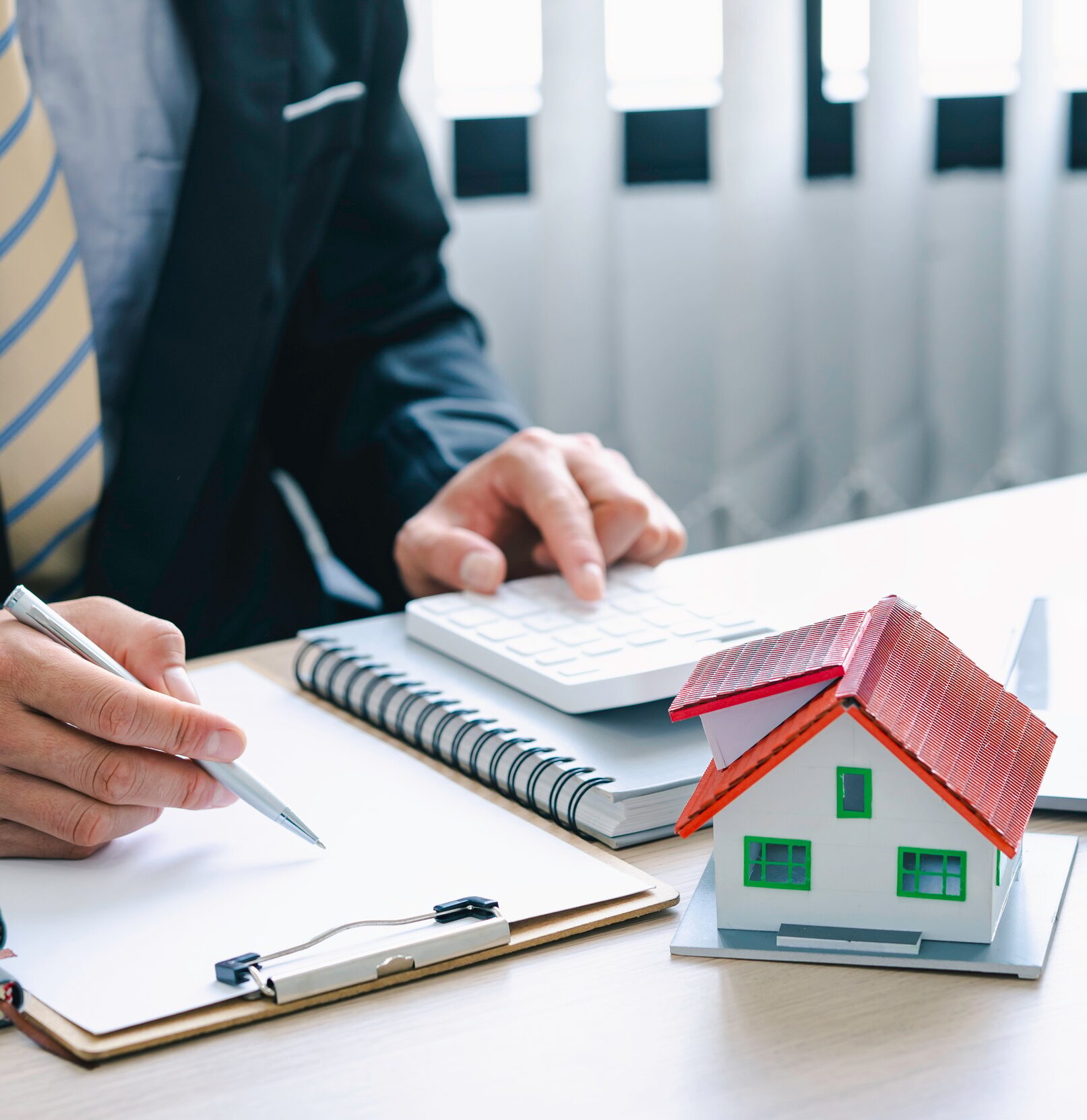 real estate agent with House model and customer discussing for the contract to buy house, insurance