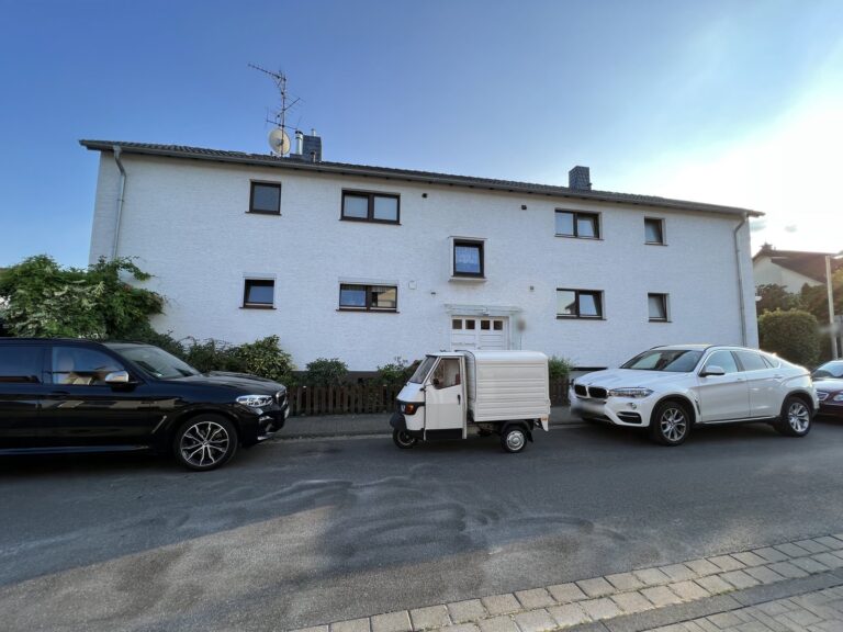 Zweigeschossiges Mehrfamilienhaus mit weißer Putzfassade